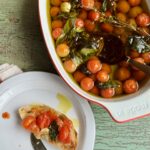 tomato confit in baking dish next to a small plate with a slice of bread and tomato confit on top