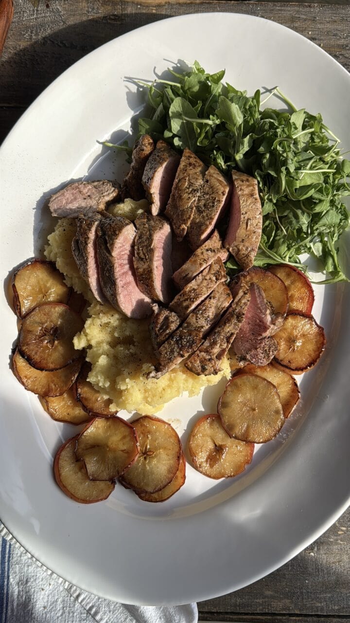 a photo of a platter with pork loin, apple slices, and potato puree