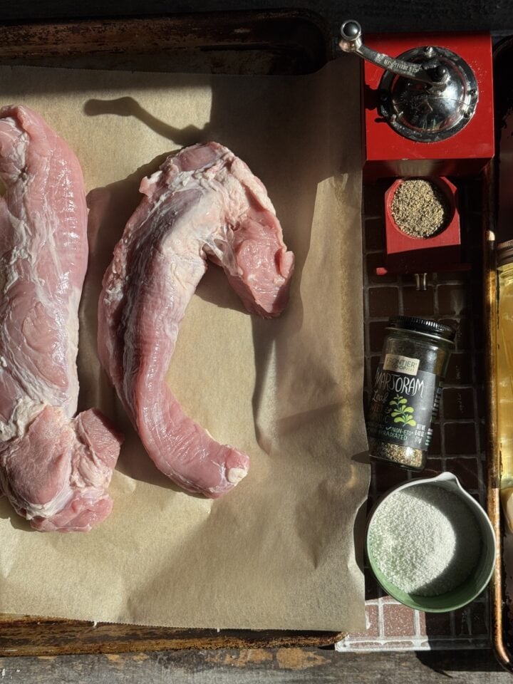 Raw pork meat and spices on a butcher paper background, ready for cooking or grilling.
