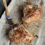 two roasted chicken breasts on a sheet pan with parchment paper