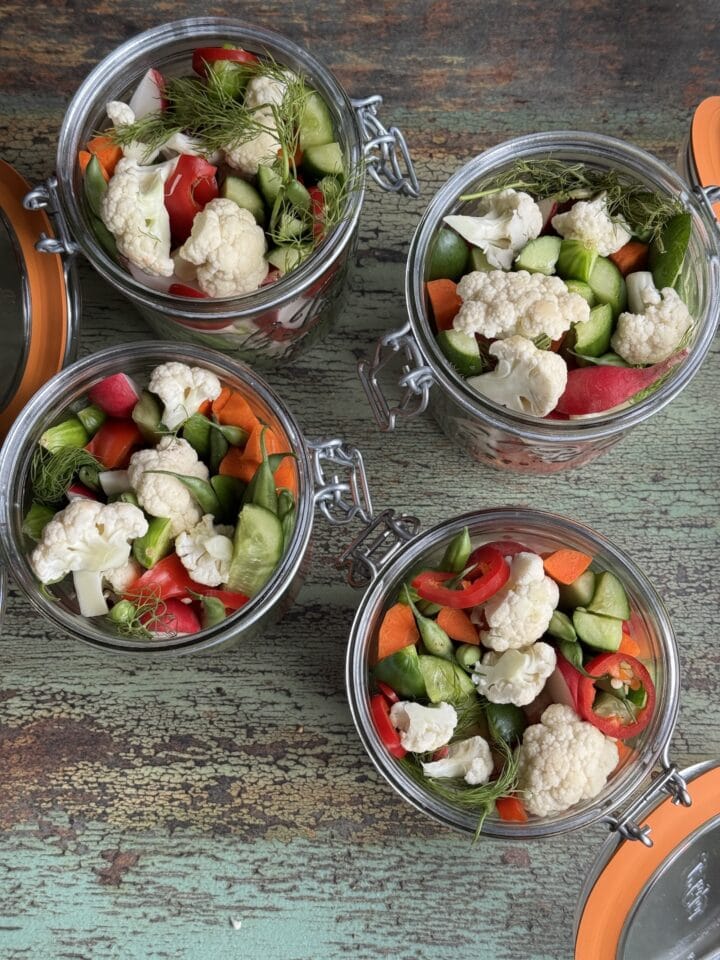four jars filled with vegetables