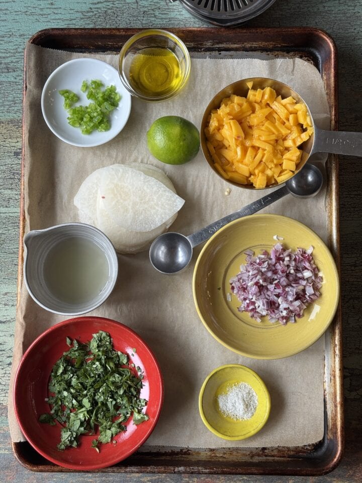 ingredients for mango salsa in small bowls on a sheet pan