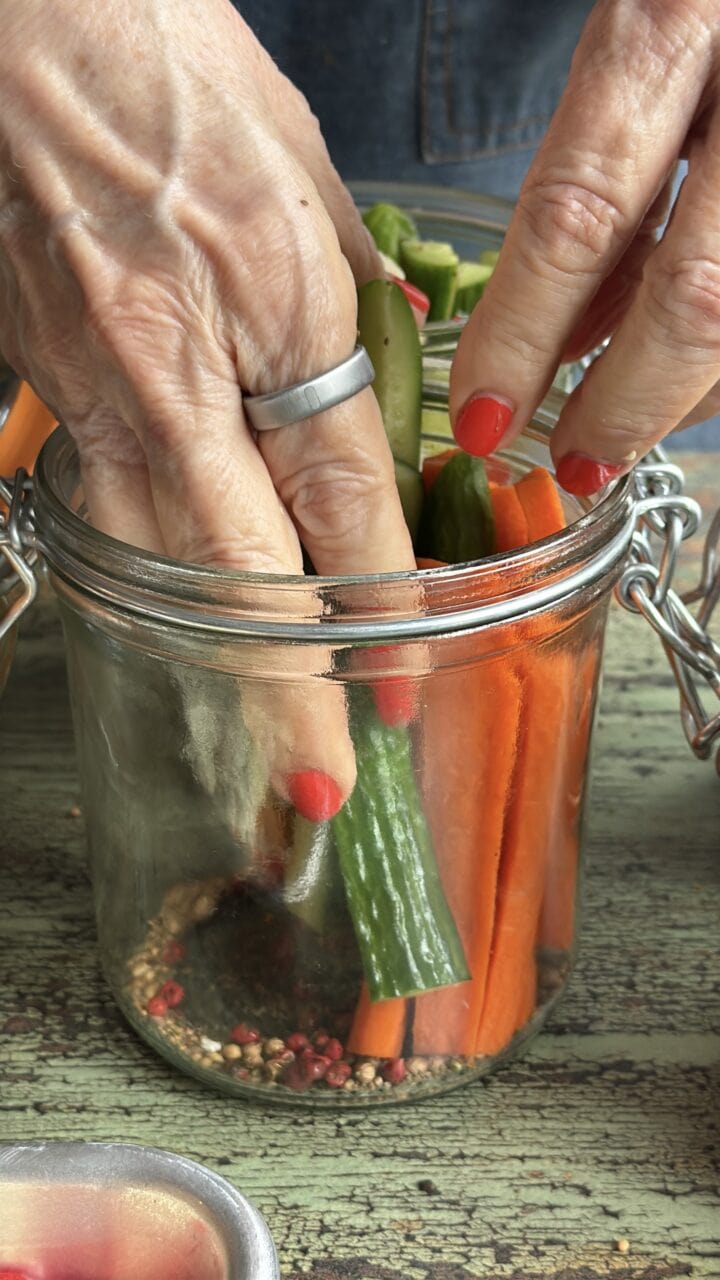 teri adding vegetables to a glass jar