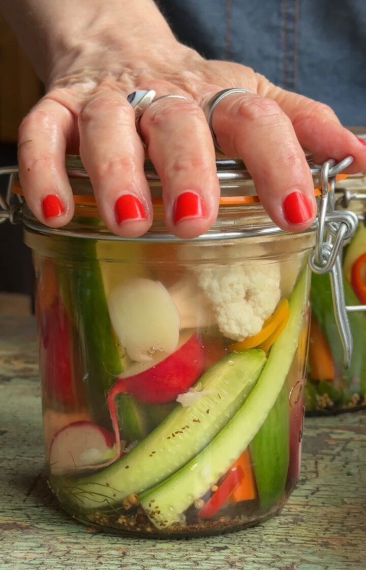 teri's hand on top of a refrigerator pickle jar