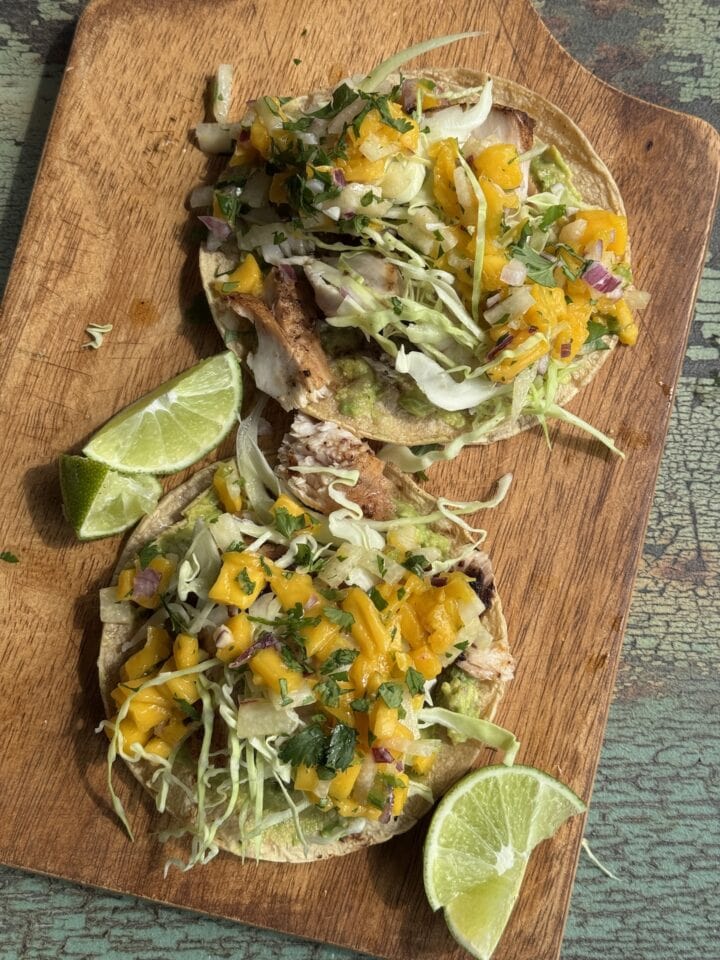 fish tacos with mango salsa on a wooden cutting board