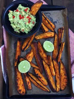sweet potato wedges on a pan with a bowl of guacamole