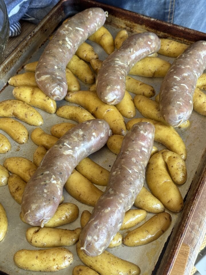 fingerling potatoes and sausage links on a sheet pan