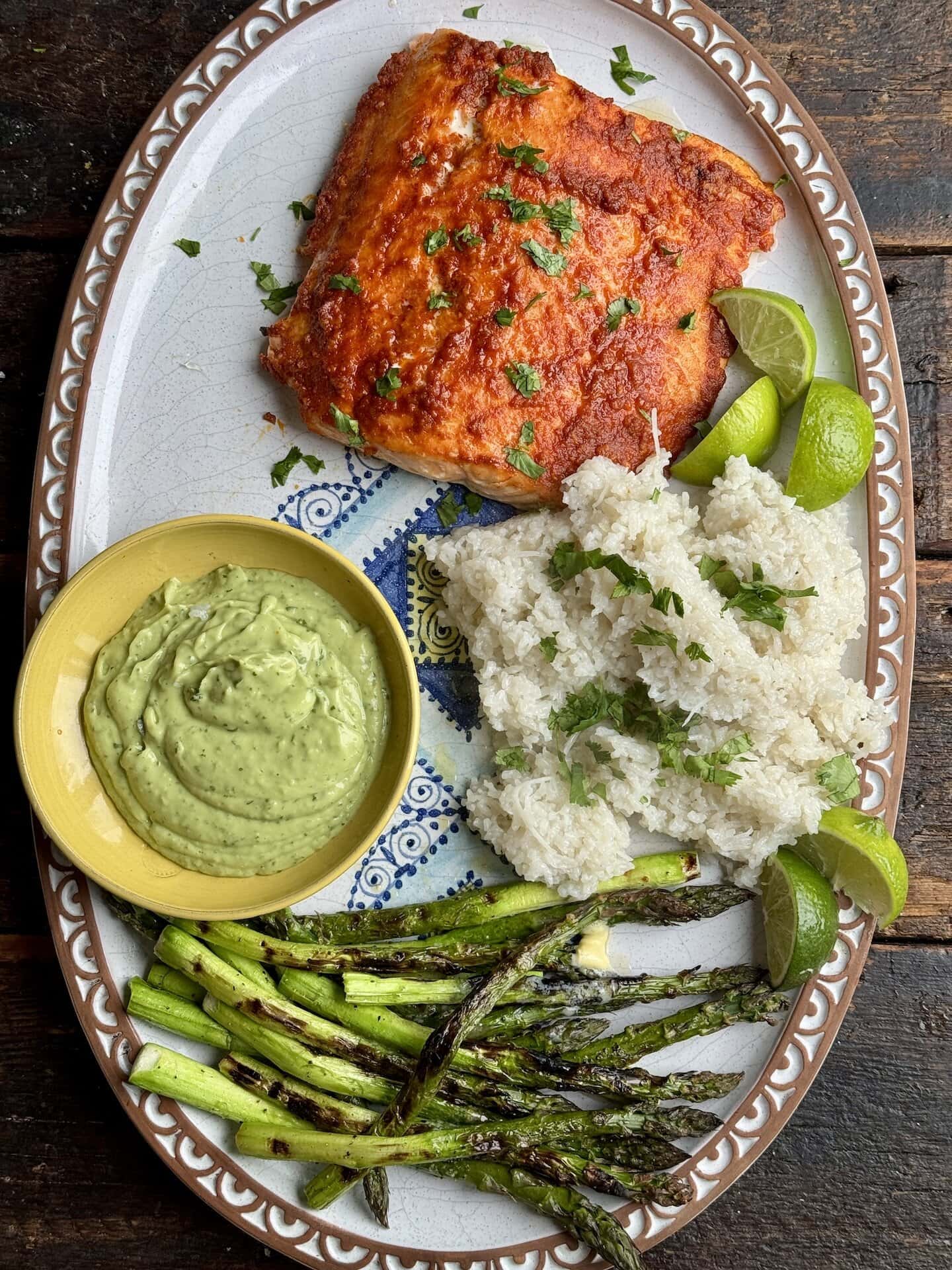 red curry glazed salmon with white rice avocado crema asparagus and lime slices