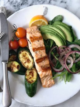 salmon, avocado, and vegetables on a white plate