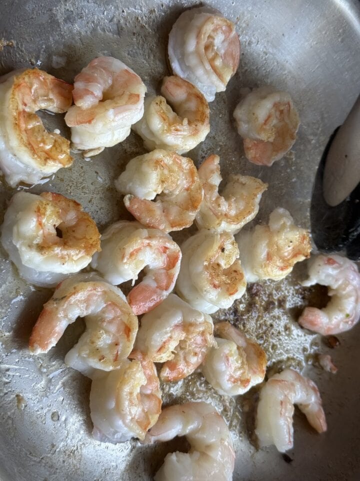 shrimp sauteeing in a stainless steel pan