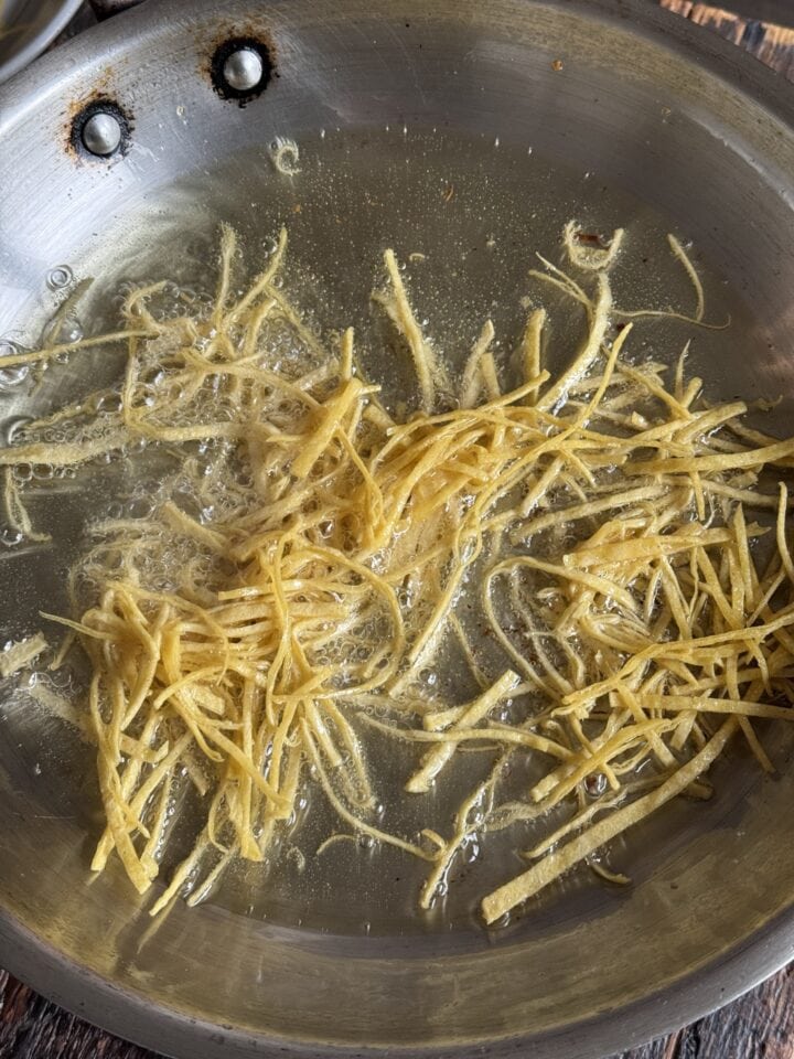 a photo of tortilla strips frying in a pan
