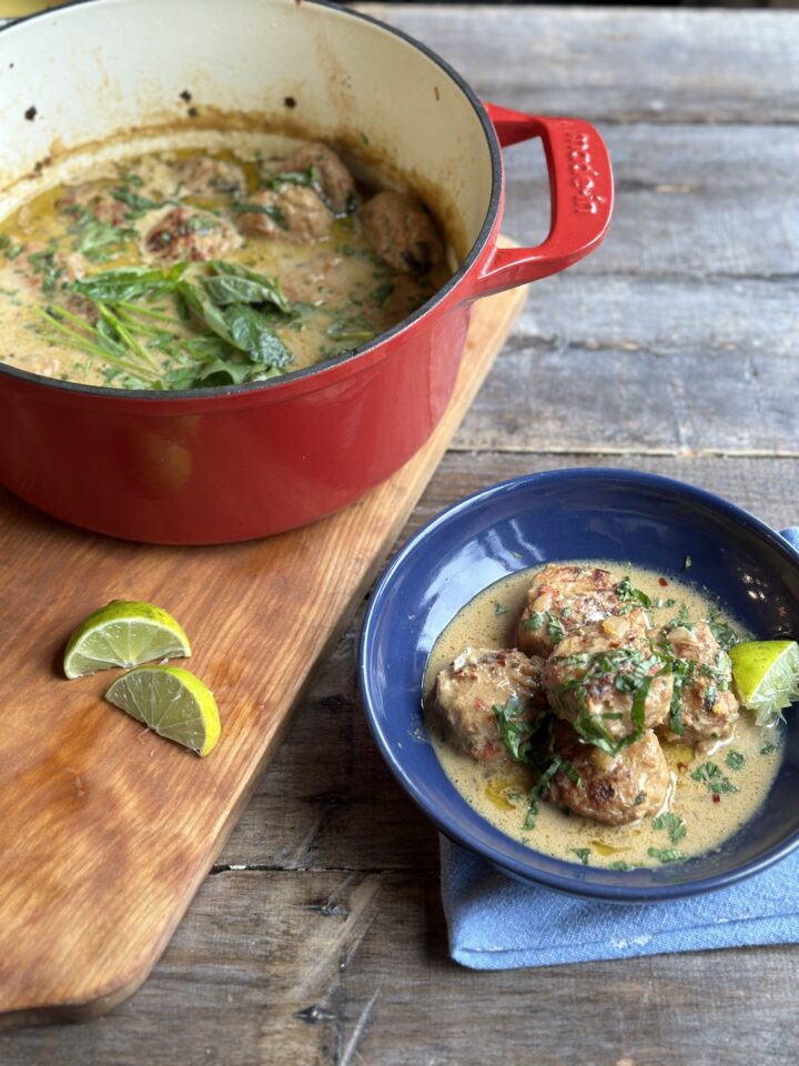 pot of green curry chicken meatballs next to pot of them.