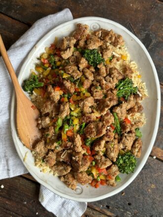 Crispy fried chicken with colorful vegetables and rice on a serving platter.