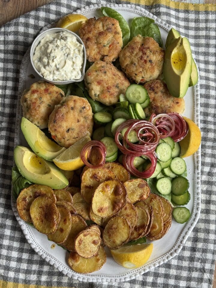 white fish cakes with salad on a white platter