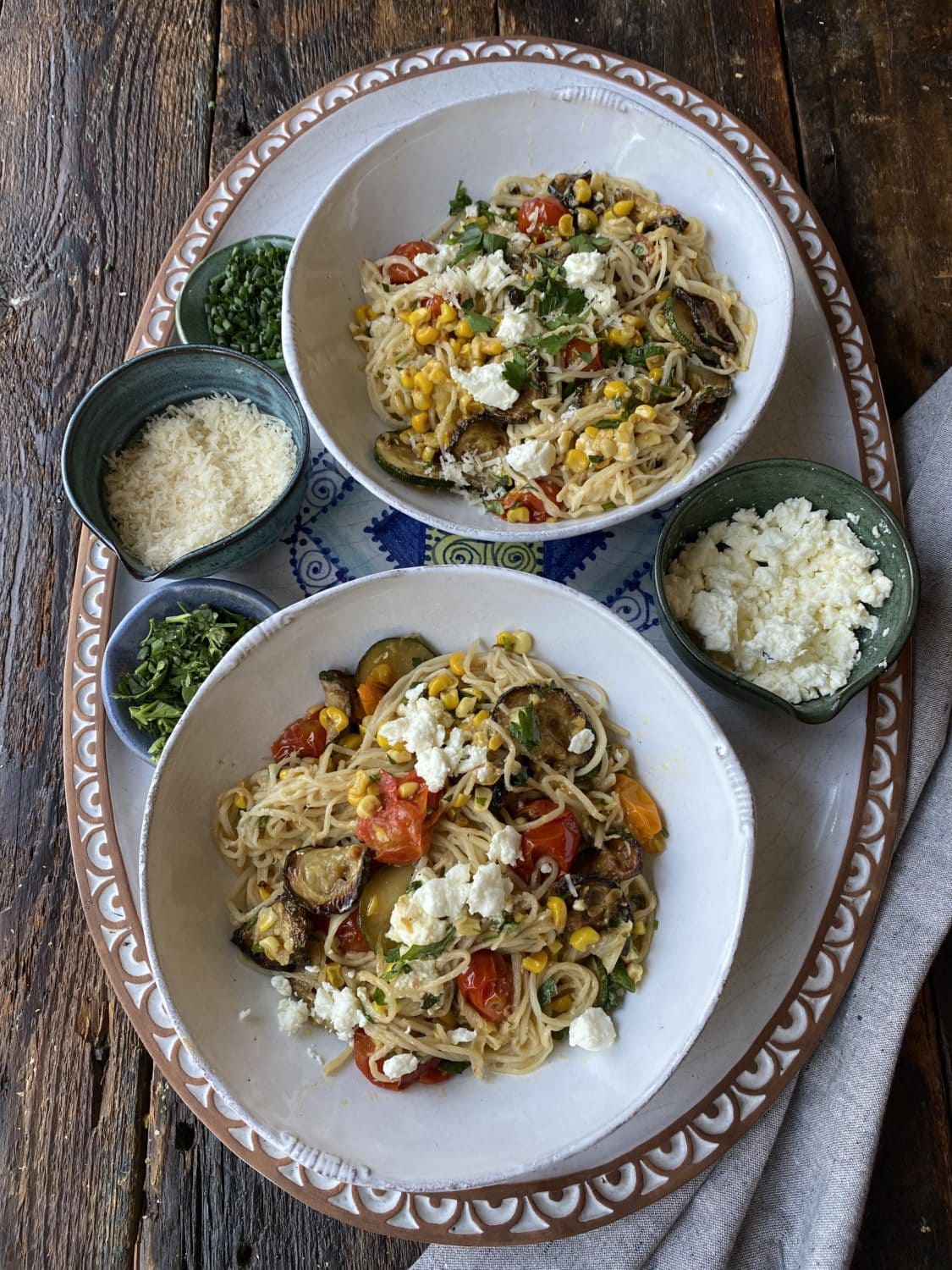two plated dishes of pasta primavera with cheese