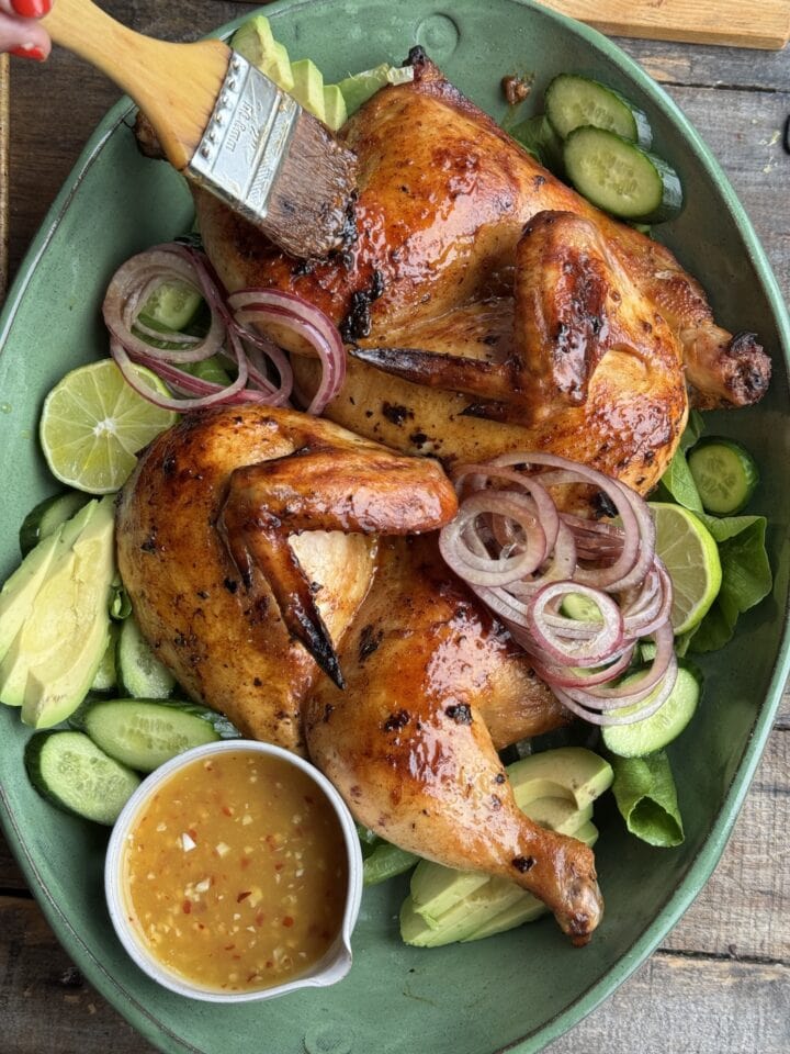 bangkok chicken on a bed of greens with sauce on the side