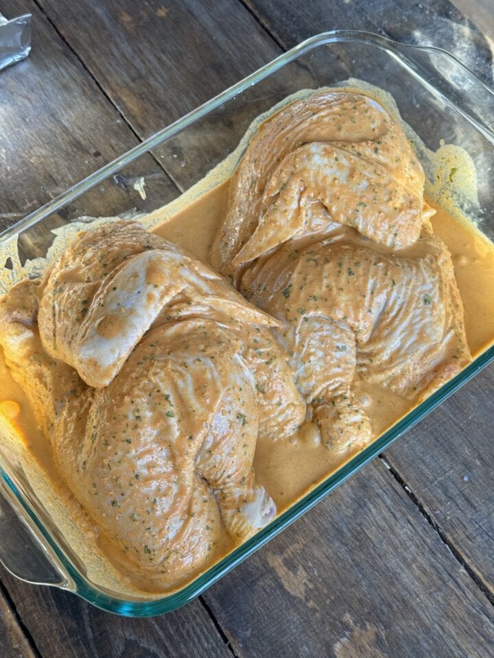 chicken halves in marinade in a glass dish