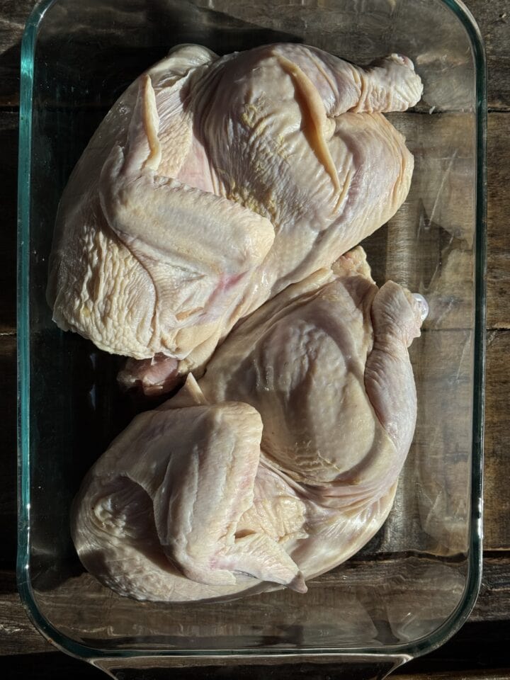 two chicken halves in a glass dish