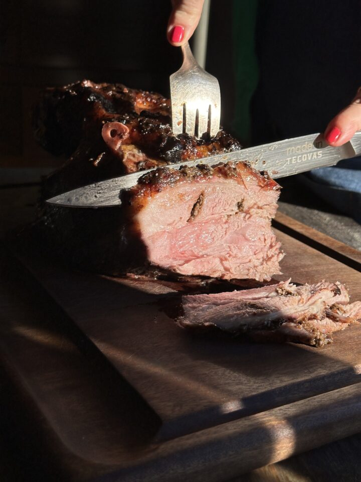 Teri slicing pork roast on a cutting board