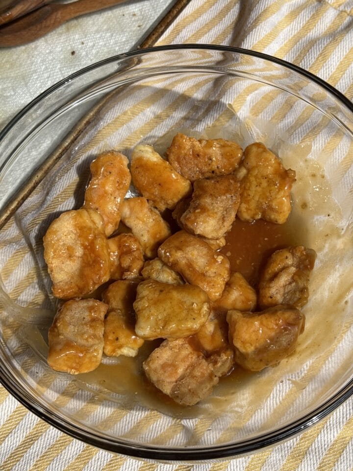 orange chicken in a glass bowl with sauce