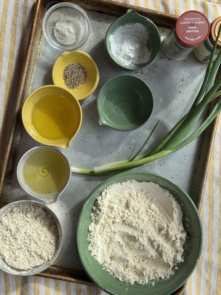 ingredients for orange chicken in small bowls on a sheet pan