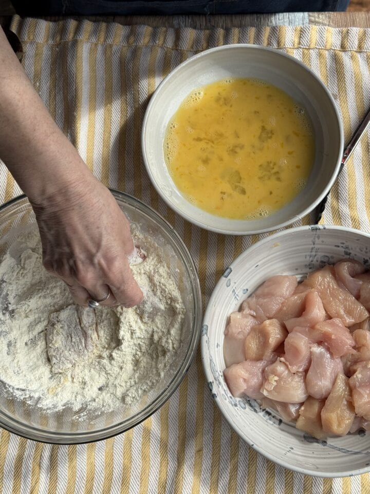 a bowl of flour, a bowl of eggs, and a bowl of chicken