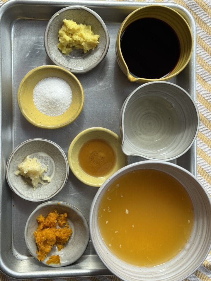 ingredients for the orange chicken sauce in small bowls on a sheet pan