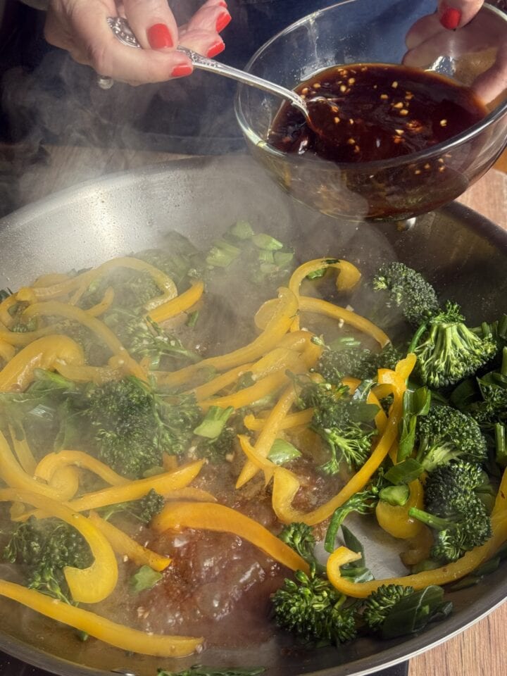 stir fry infuser pouring into a pan with vegetables in it