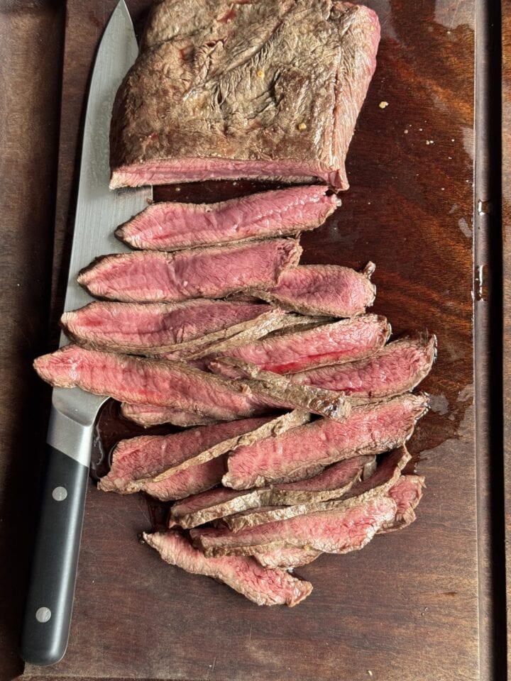 slice flat iron steak on a wooden cutting board