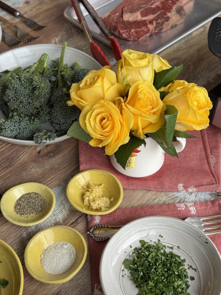 ingredients for steak with mashed potatoes on a table with yellow flowers
