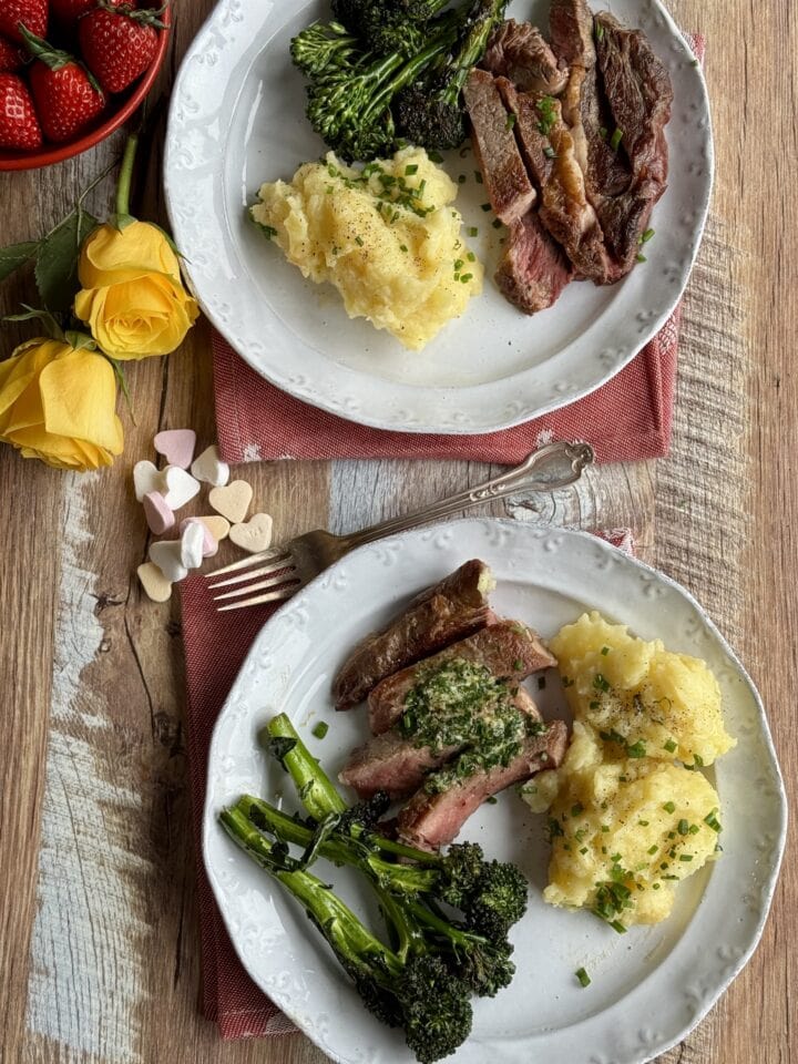 two servings of ribeye on white plates with mashed potatoes and broccolini