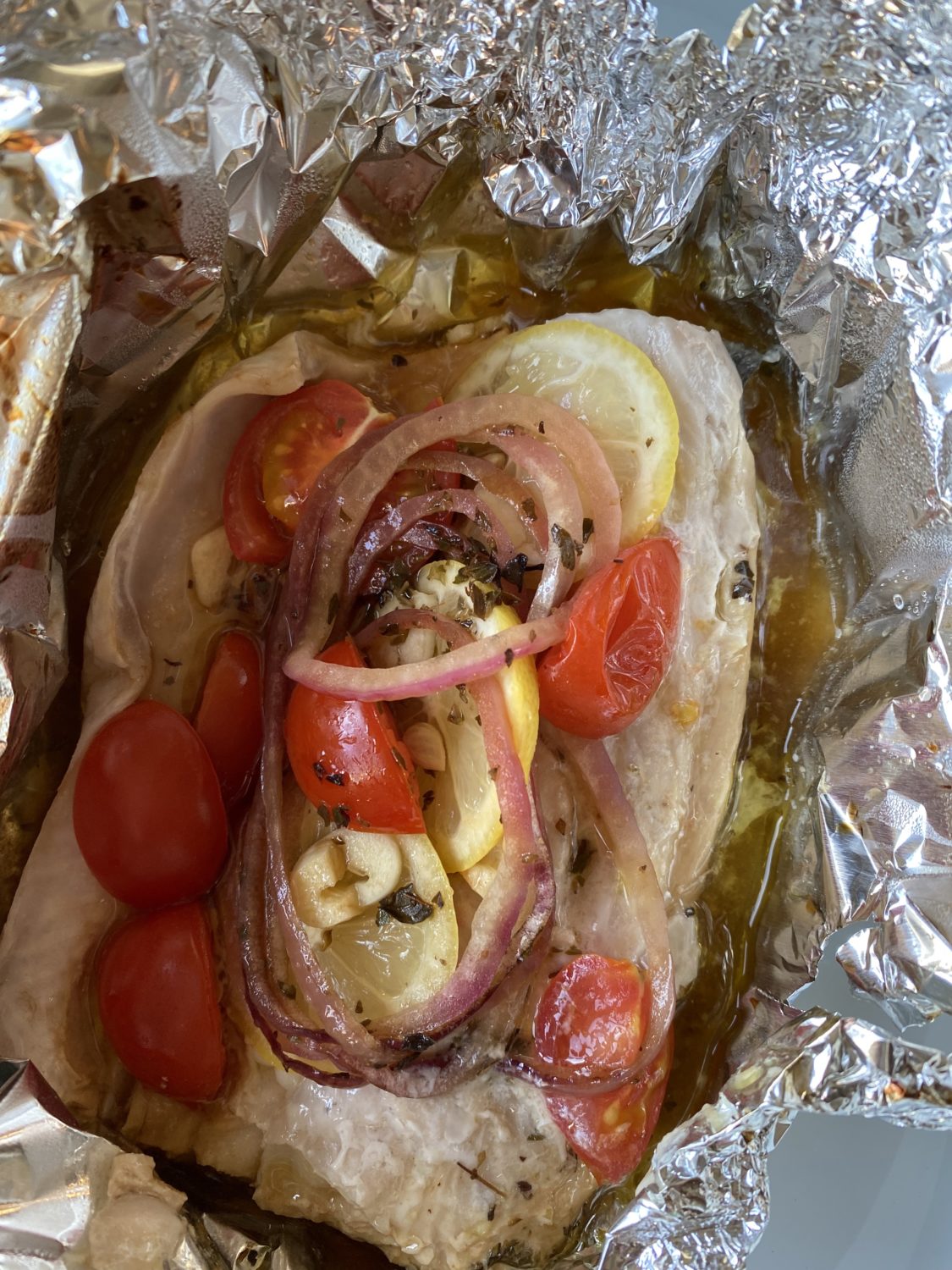 white fish in foil with tomatoes and onions