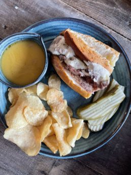 french dip sandwich with sauce and chips