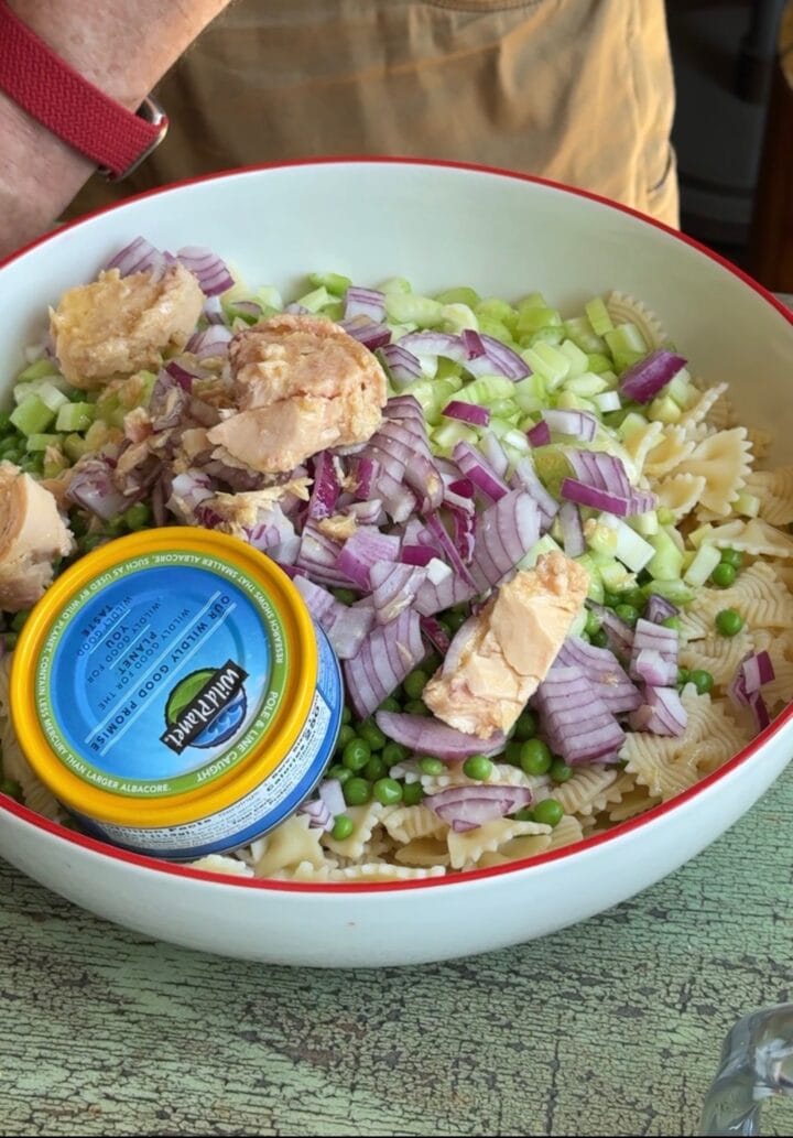 tuna added to a large bowl with pasta and vegetables