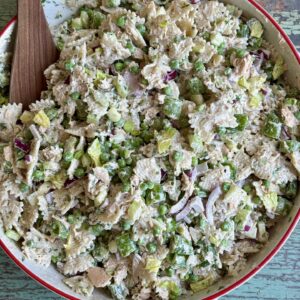 tuna pasta salad in a serving bowl with a wooden spoon in it