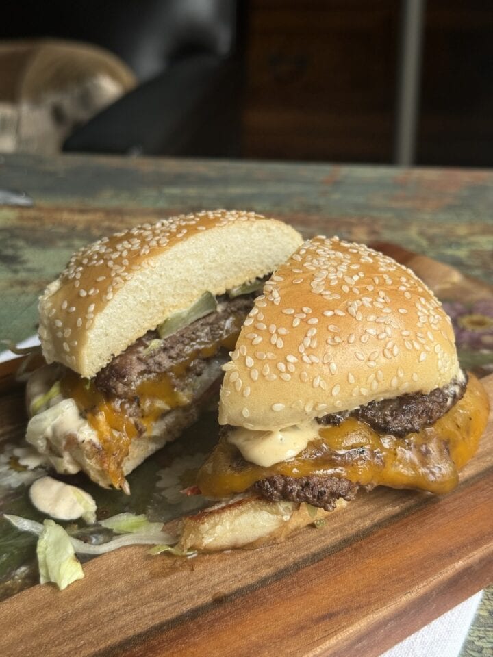 a smashburger cut in half on a wooden cutting board