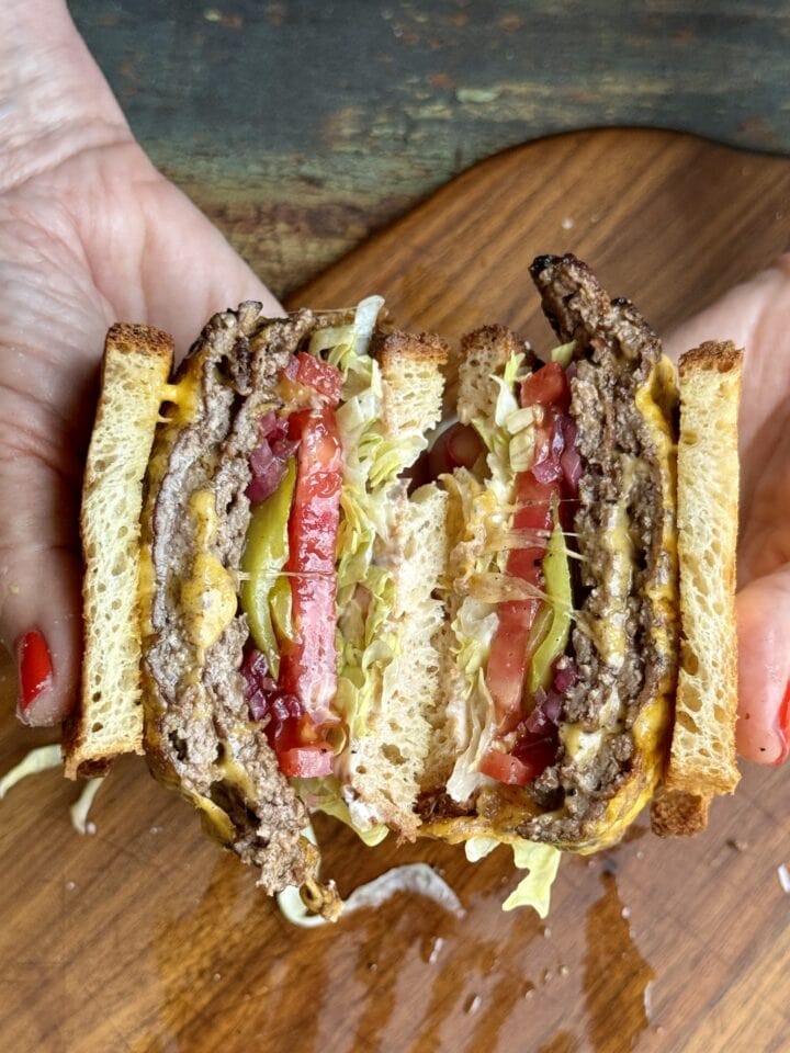 smashburger patty melt cut in half and held in someone's hands