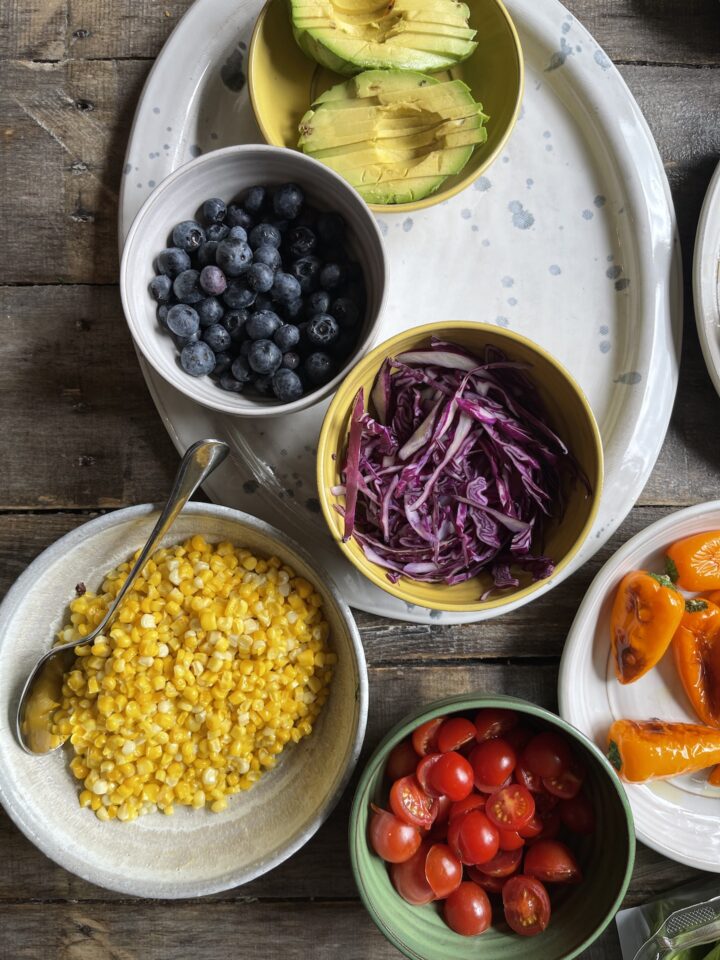 Ingredients for Rainbow Salad with Chicken; blueberries, corn, red cabbage, roasted orange mini peppers, avocado.