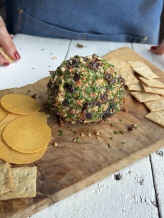 Finished cheeseball on a wood board.