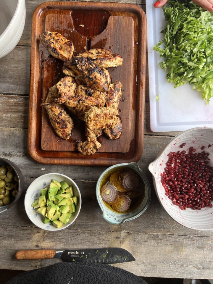 chicken on cutting board surrounded by bowls of salad toppings