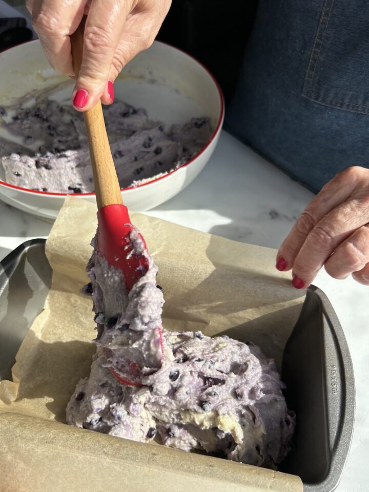 Using a red spatula to transfer cake batter into pan