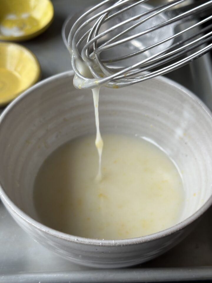 Whisk dripping with lemon icing into bowl of icing.