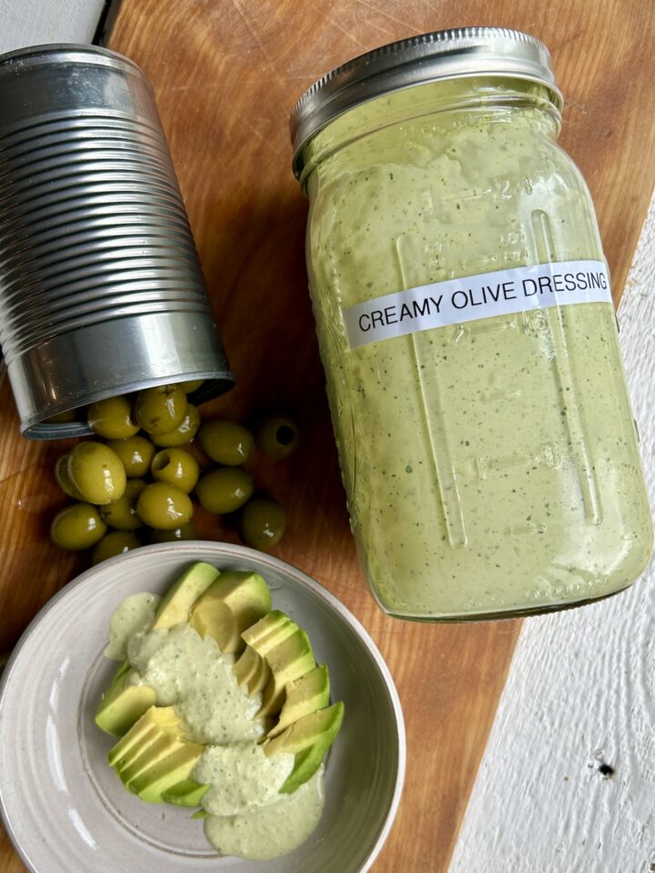 creamy olive dressing jar next to olive can & avocado slices
