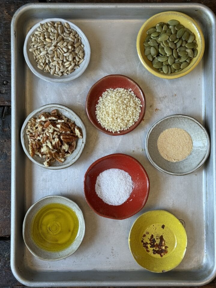 nuts seeds oil salt and spices in small bowls on a metal sheet tray