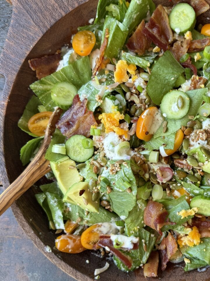 tossed salad in wood bowl with wood utensil
