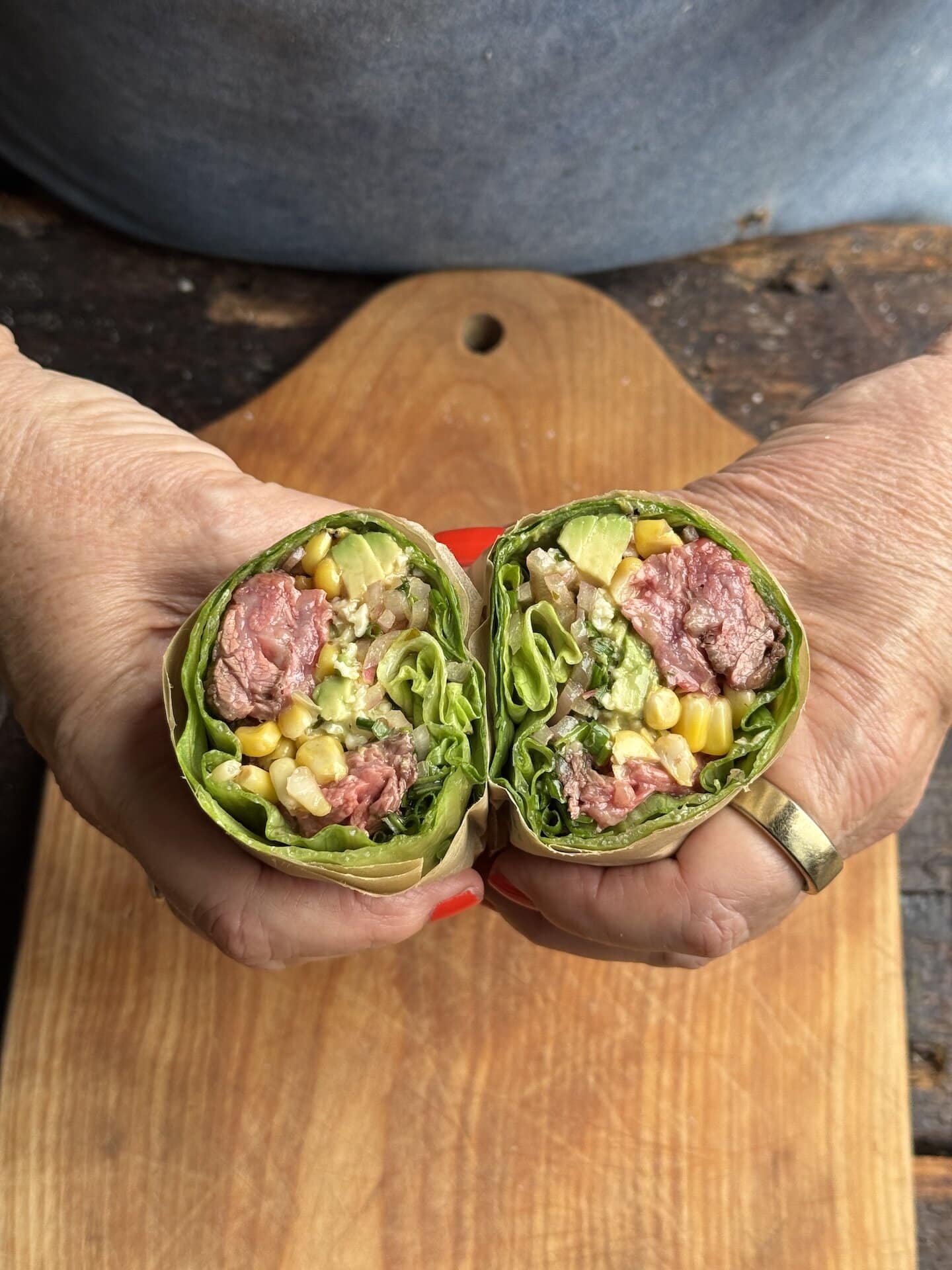 a photo of teri's hands holding a steak wrap above a cutting board