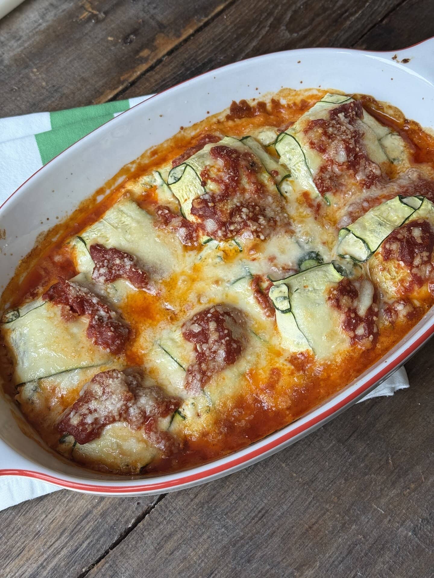 a photo of zucchini roll up lasagna in a white oval baking dish