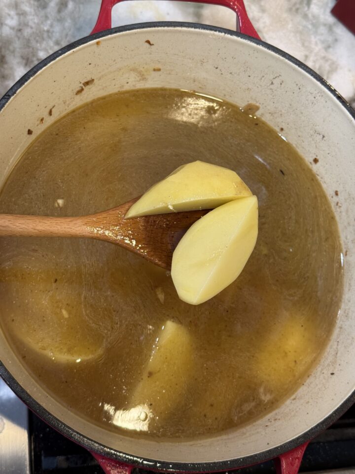 adding potatoes to the soup pot