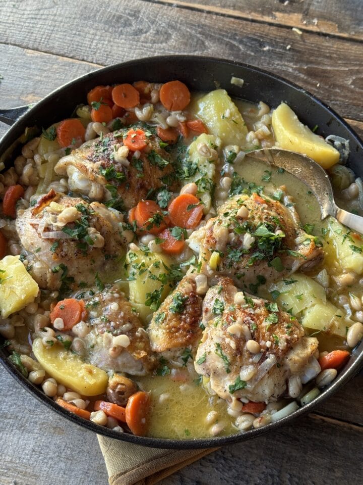 chicken thighs with potatoes and beans in a skillet