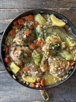 chicken thighs with potatoes and beans in a skillet